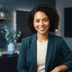 A smiling diverse woman looking at the camera in a modern, professional office environment with blue and charcoal accents.